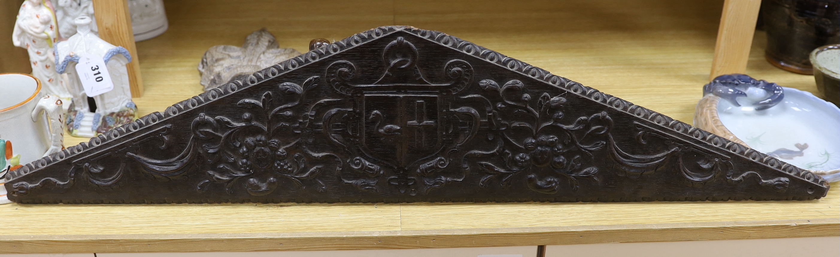 Three religious carvings; three carved Acanthus leafed pew finials, a two section carved Alms coin box and a triangular carved panel, largest 95cm long